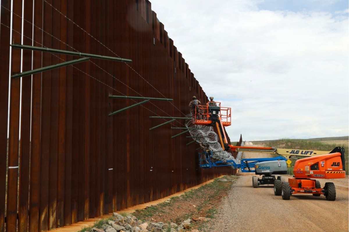 A section of border fence and access road near a port of entry.